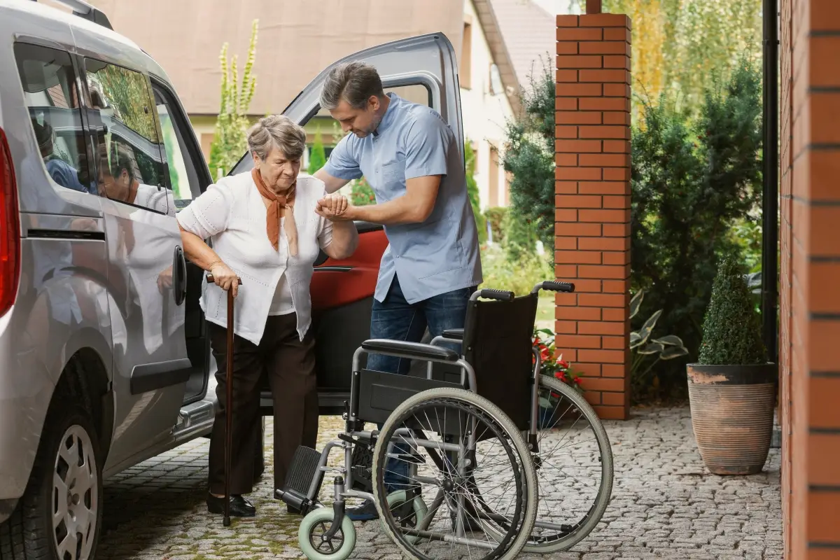 Son helping his mother get out of the car and situated in a wheelchair